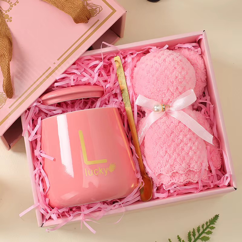 Pink mug, soft blanket and gold spoon arranged in a gift box